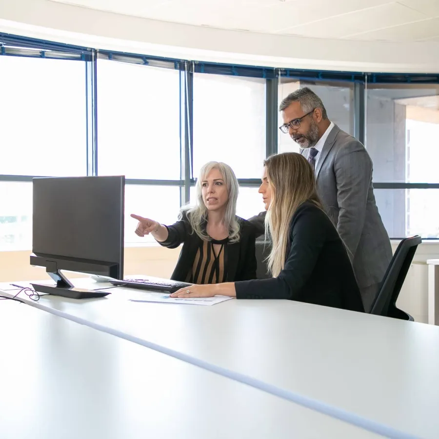 Three colleagues reviewing work together at a desk in an office